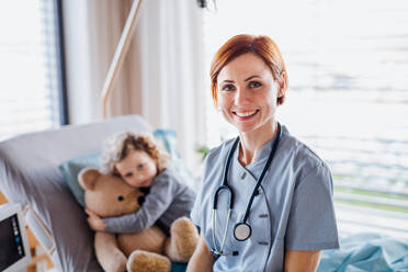 Freundliche Ärztin und kleines Mädchen im Bett im Krankenhaus, Blick in die Kamera. - HPIF13052