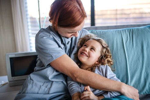 Freundliche Ärztin mit Stethoskop im Gespräch mit kleinem Mädchen im Bett im Krankenhaus. - HPIF13056