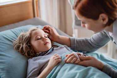 Eine fürsorgliche Mutter besucht ihre kleine Tochter im Bett im Krankenhaus. - HPIF13063