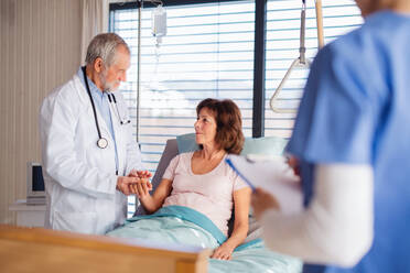 Ein Arzt und eine Krankenschwester untersuchen einen älteren Patienten im Bett eines Krankenhauses. - HPIF13068