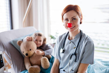 Freundliche Ärztin mit Stethoskop bei der Untersuchung eines kleinen Mädchens im Bett im Krankenhaus. - HPIF13080