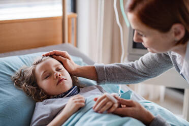 Eine fürsorgliche Mutter besucht ihre schlafende kleine Tochter im Bett im Krankenhaus. - HPIF13092