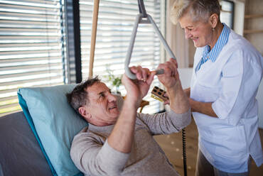 Eine Pflegekraft hilft einem gelähmten älteren Patienten im Krankenhaus. - HPIF13106