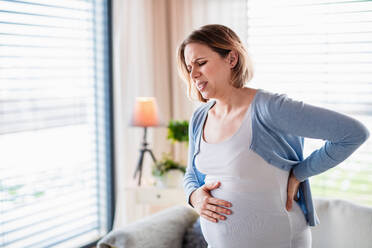 Porträt einer schwangeren Frau mit Schmerzen zu Hause in Taillenhöhe. - HPIF13137