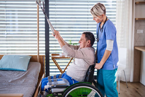 Eine Pflegekraft und ein älterer Patient im Rollstuhl, Konzept der Physiotherapie. - HPIF13149