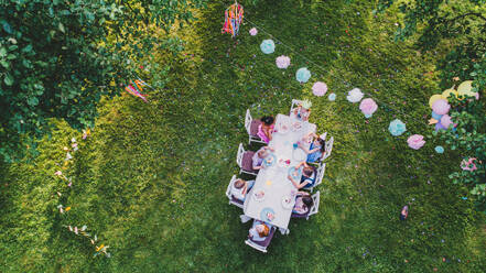Luftaufnahme von kleinen Kindern sitzen am Tisch auf Sommergarten Party, Geburtstagsfeier Konzept. - HPIF13168