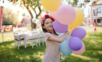 Small girl outdoors in garden in summer, playing with balloons. A celebration concept. - HPIF13203