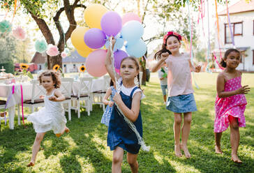 Kleine Kinder im Garten im Sommer, die mit Luftballons spielen, ein Festkonzept. - HPIF13204