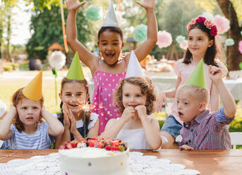 Down-Syndrom-Kind mit Freunden auf Geburtstagsfeier im Freien im Garten im Sommer. - HPIF13212