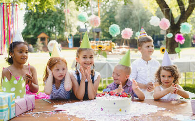 Down-Syndrom-Kind mit Freunden auf Geburtstagsfeier im Freien im Garten im Sommer. - HPIF13214