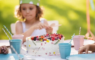 Frontansicht des kleinen Mädchens mit Kuchen feiern Geburtstag im Freien im Garten im Sommer, Party-Konzept. - HPIF13223