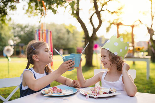 Glückliche kleine Mädchen sitzen und essen am Tisch auf Sommergarten Party, Geburtstagsfeier Konzept. - HPIF13231