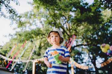 Low angle view of small boy standing outdoors on garden party, playing. Celebration concept. - HPIF13238