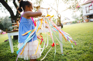 Kleines Mädchen draußen im Garten im Sommer, spielen mit Regenbogen Hand Drachen. ein Fest Konzept. - HPIF13247