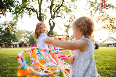 Kleine Mädchen draußen im Garten im Sommer, spielen mit Regenbogen Hand Drachen. ein Fest Konzept. - HPIF13248