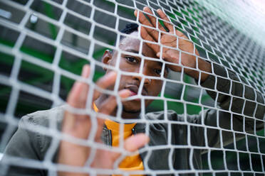 Frustrated young black man behind net outdoors in city, black lives matter and discrimination concept. - HPIF13256