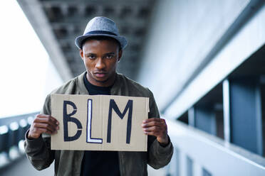 Junger Mann mit BLM-Schild im Freien in der Stadt, Konzept 