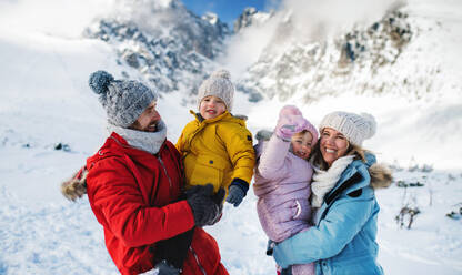 Frontalaufnahme von Vater und Mutter mit zwei kleinen Kindern in winterlicher Natur, stehend im Schnee. - HPIF13309