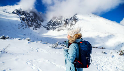 Side view portrait of happy smiling woman standing in snowy winter nature. - HPIF13313