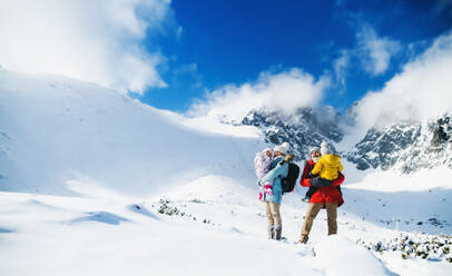 Frontalaufnahme von Vater und Mutter mit kleinem Sohn in winterlicher Natur, stehend im Schnee. - HPIF13318