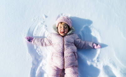 Top view Porträt der fröhlichen kleinen Kleinkind Mädchen im Schnee im Winter Natur liegen, machen Engel. - HPIF13320