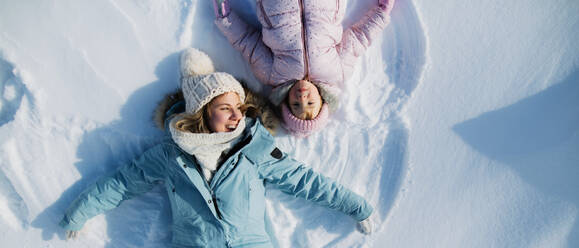 Top view Porträt der fröhlichen Mutter mit kleinen Kleinkind Tochter im Schnee im Winter Natur liegen. - HPIF13321