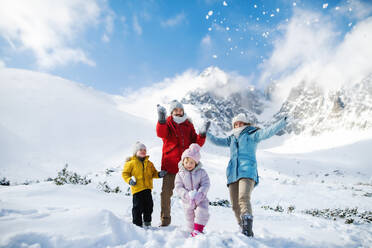 Frontalaufnahme von Vater und Mutter mit zwei kleinen Kindern in winterlicher Natur, die im Schnee spielen. - HPIF13323