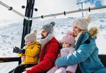 Glückliche Familie mit kleinem Sohn und Tochter in einer Seilbahnkabine, Urlaub in verschneiter Winternatur. - HPIF13331