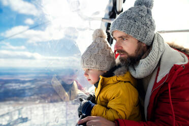 Father with small son inside a cable car cabin, holiday in snowy winter nature. Copy space. - HPIF13334