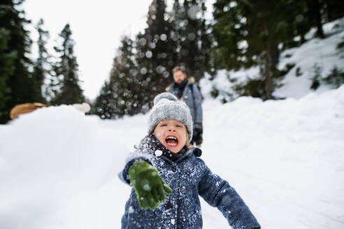 Frontansicht eines glücklichen kleinen Kindes, das im Schnee spielt, Urlaub in der winterlichen Natur. - HPIF13343