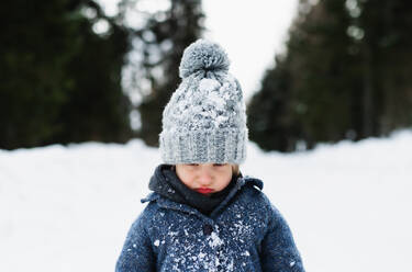 Front view of unhappy and sad small child standing in snow, holiday in winter nature. - HPIF13347