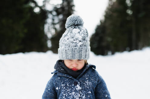 Frontansicht eines unglücklichen und traurigen kleinen Kindes, das im Schnee steht, Urlaub in der winterlichen Natur. - HPIF13347