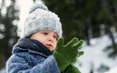 Glückliches kleines Kind, das im Schnee steht, Urlaub in der winterlichen Natur. - HPIF13349