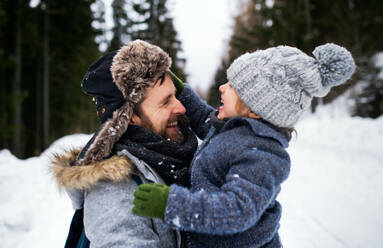 Seitenansicht eines Vaters mit seinem kleinen Sohn in verschneiter Winternatur, die sich unterhalten und lachen. - HPIF13355