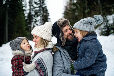 Side view portrait of father and mother with two small children in winter nature, standing in the snow. - HPIF13363