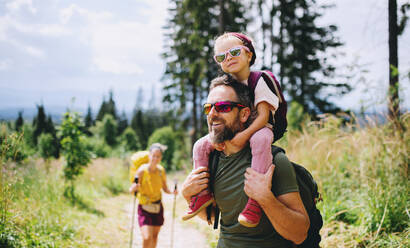 Vorderansicht einer Familie mit Kleinkind beim Wandern in der sommerlichen Natur. - HPIF13379