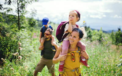 Frontansicht einer Familie mit kleinen Kindern beim Wandern in der sommerlichen Natur. - HPIF13385