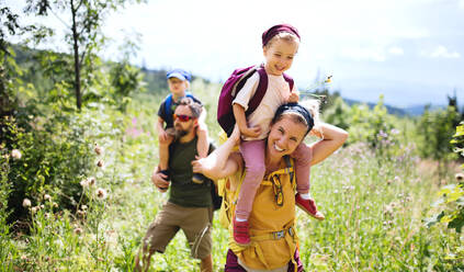 Frontansicht einer Familie mit kleinen Kindern beim Wandern in der sommerlichen Natur. - HPIF13386