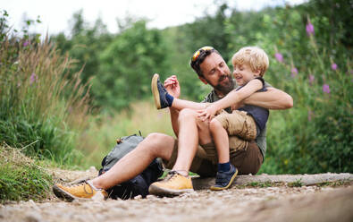 Mature father with small son hiking outdoors in summer nature, sitting and resting. - HPIF13400