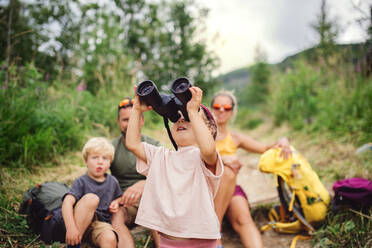 Front view of family with small children hiking outdoors in summer nature, sitting and resting. - HPIF13410