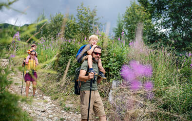 Glückliche Familie mit kleinen Kindern beim Wandern im Sommer in der Natur, beim Spazierengehen. - HPIF13418