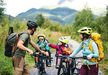 Glückliche Familie mit kleinen Kindern beim Radfahren in der sommerlichen Natur, beim Ausruhen. - HPIF13430