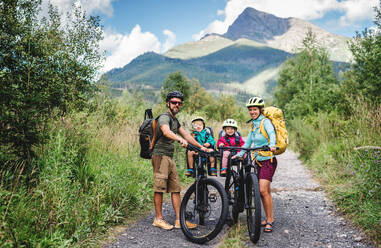 Glückliche Familie mit kleinen Kindern beim Radfahren in der sommerlichen Natur. - HPIF13431