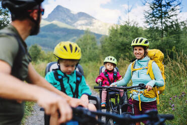 Glückliche Familie mit kleinen Kindern beim Radfahren in der sommerlichen Natur, Tatra-Gebirge, Slowakei. - HPIF13432