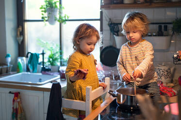 Glücklicher kleiner Junge und Mädchen drinnen in der Küche zu Hause, die beim Kochen helfen. - HPIF13485