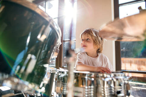 Porträt eines glücklichen kleinen Jungen, der zu Hause Schlagzeug spielt. - HPIF13504