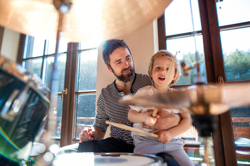 Vorderansicht des Porträts eines kleinen Jungen mit seinem Vater, der zu Hause Schlagzeug spielt. - HPIF13506