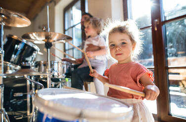 Portrait of happy small girl indoors at home, playing drums. - HPIF13510
