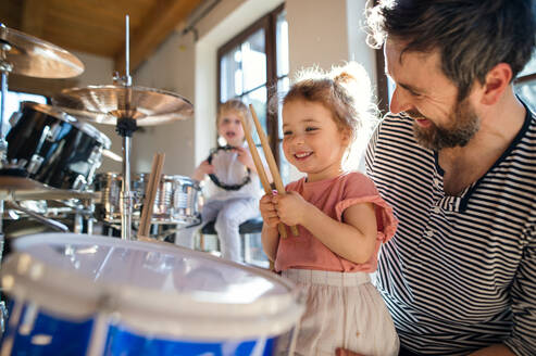 Porträt von glücklichen kleinen Kindern mit Vater zu Hause, die Schlagzeug spielen. - HPIF13513