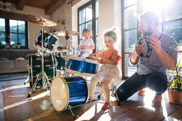Porträt von glücklichen kleinen Kindern mit Vater zu Hause, die Schlagzeug spielen. - HPIF13514